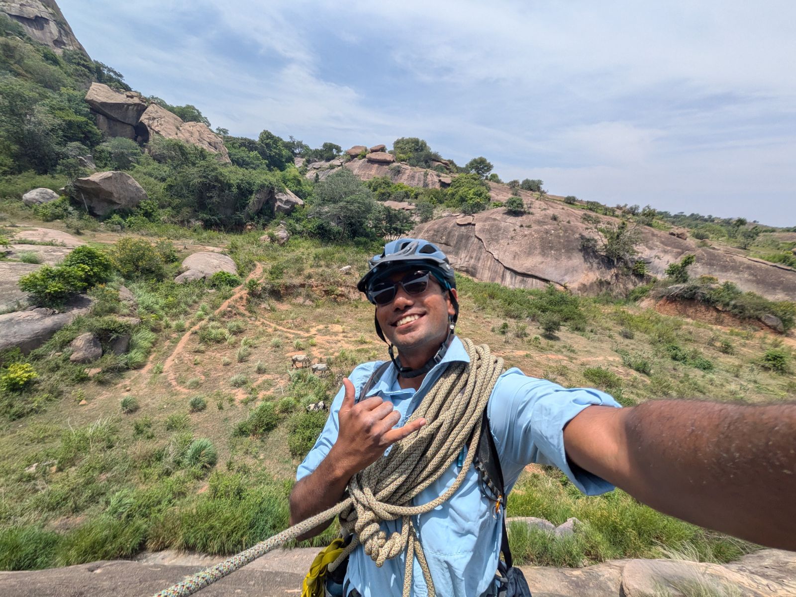 Manoj with a coiled rope at the top of a granite crag