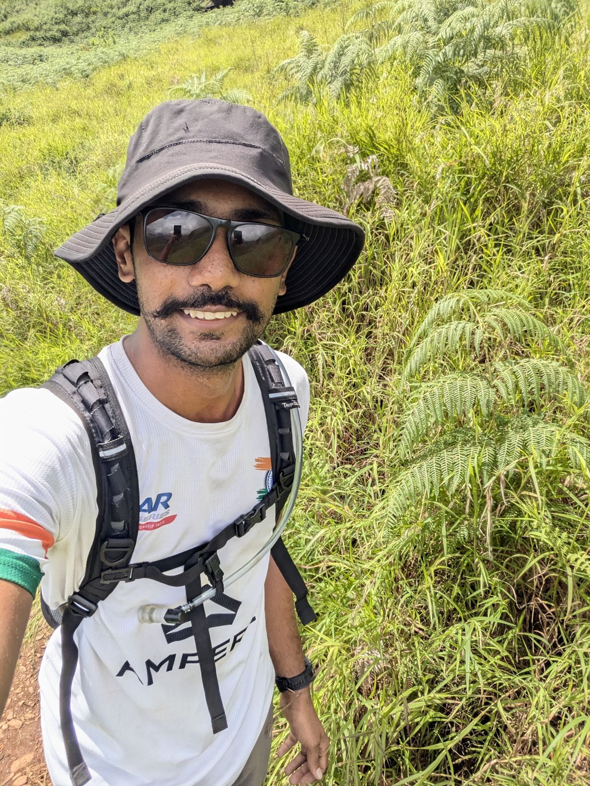 Manoj on a grassy trail with a hydration pack